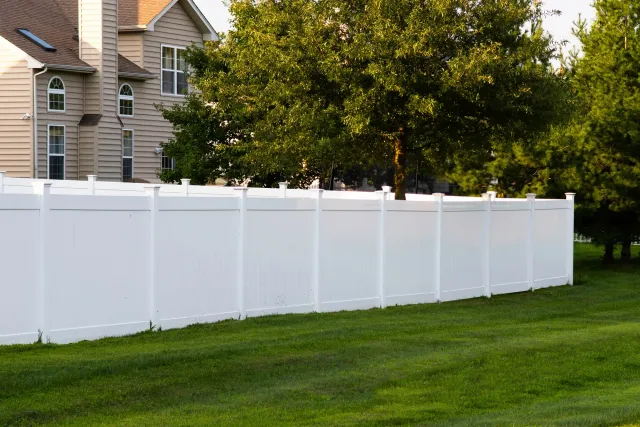 White vinyl privacy fence along a backyard lawn